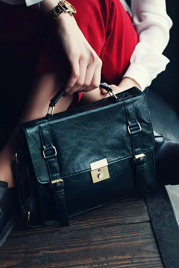 Close up of woman sitting down with a black leather briefcase at her feet.