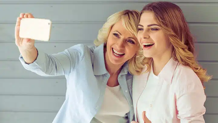 Mother and daughter laugh while taking a selfie.