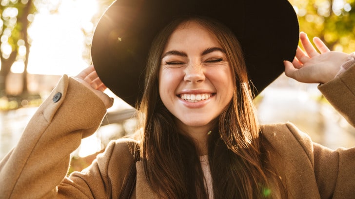 Smiling woman follows two fall fashion rules, wearing a hat and a nice coat.