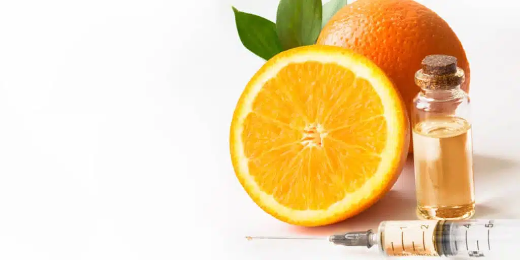 Orange and vial of vitamin C serum